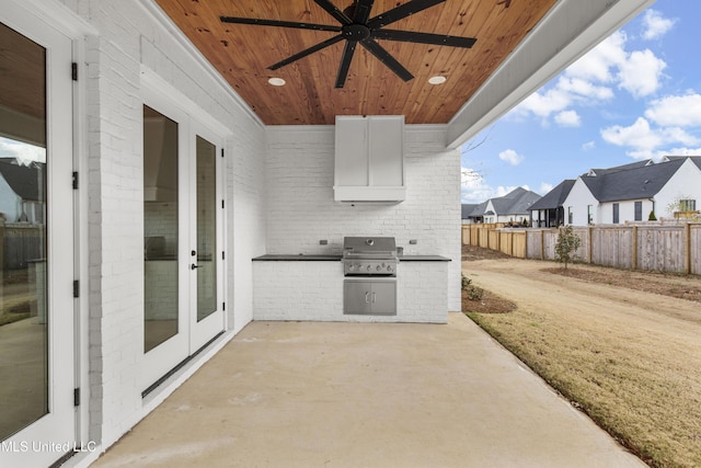 view of patio featuring a residential view, grilling area, fence, exterior kitchen, and french doors