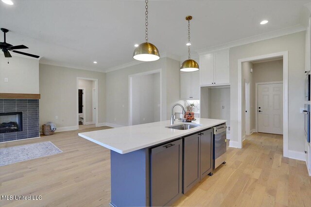 kitchen featuring dishwasher, light hardwood / wood-style flooring, sink, decorative light fixtures, and white cabinetry