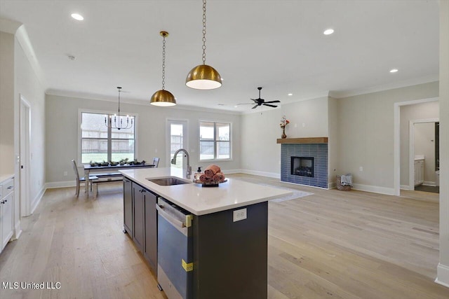 kitchen featuring an island with sink, hanging light fixtures, light hardwood / wood-style flooring, sink, and stainless steel dishwasher