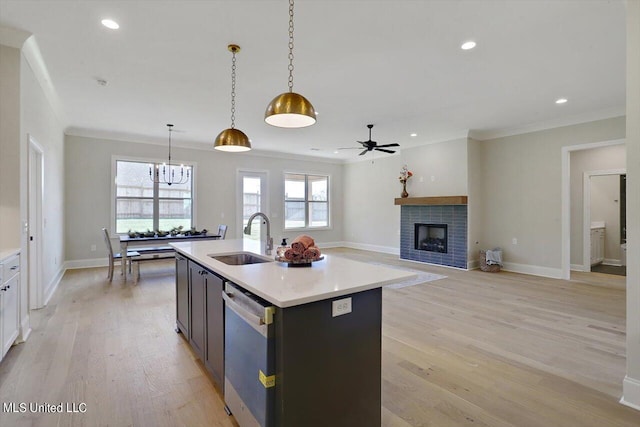 kitchen featuring light countertops, ceiling fan with notable chandelier, dishwasher, a fireplace, and a sink