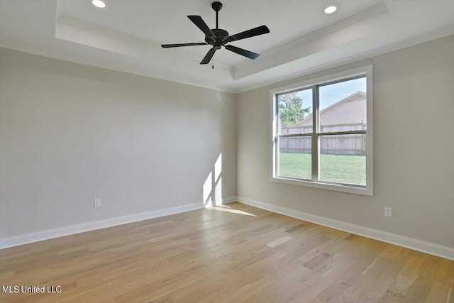 unfurnished room with recessed lighting, baseboards, light wood-type flooring, a ceiling fan, and a tray ceiling