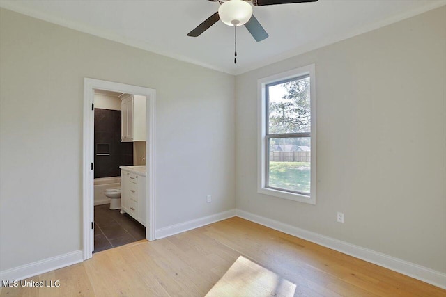 unfurnished bedroom with ceiling fan, ensuite bath, and hardwood / wood-style floors