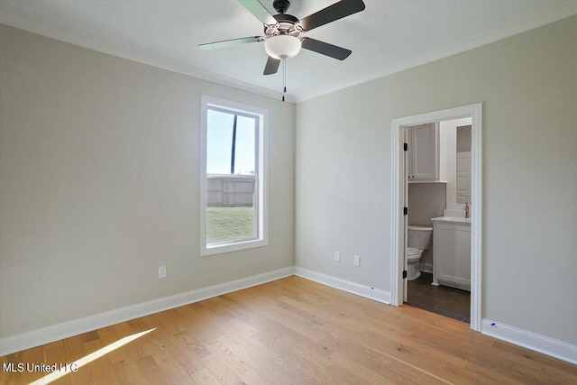 unfurnished bedroom featuring ensuite bath, baseboards, ceiling fan, and light wood-style floors