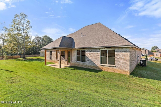 back of property featuring a lawn, roof with shingles, a patio, and brick siding