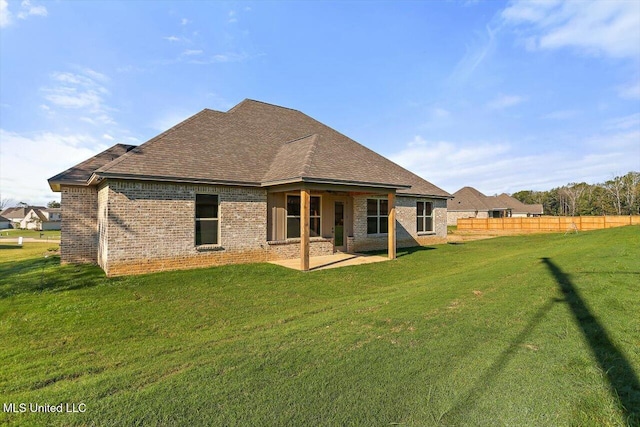 back of property with a patio, fence, a lawn, and brick siding