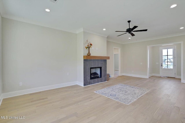 unfurnished living room featuring light wood-style flooring, ceiling fan, baseboards, ornamental molding, and a brick fireplace