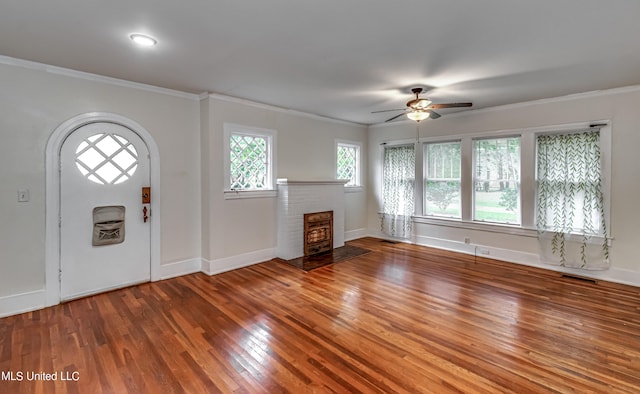 entrance foyer with crown molding, hardwood / wood-style flooring, a wood stove, and ceiling fan