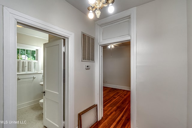 hall with dark wood-type flooring and a chandelier