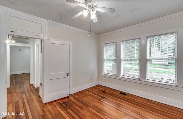 empty room with ornamental molding, ceiling fan, a healthy amount of sunlight, and dark hardwood / wood-style flooring