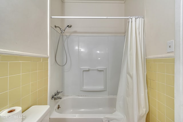 bathroom featuring toilet, shower / tub combo with curtain, and tile walls