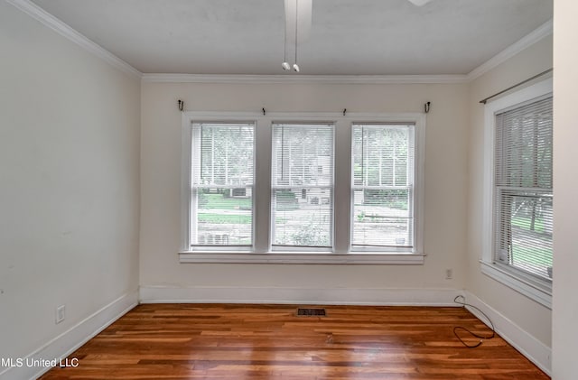 empty room with crown molding, wood-type flooring, and a wealth of natural light