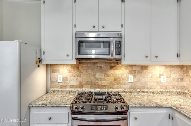 kitchen featuring white cabinetry, light stone counters, appliances with stainless steel finishes, and decorative backsplash