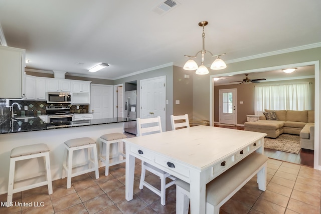 28121 Dusty Ln, Picayune, MS 39466 - kitchen with appliances with stainless steel finishes, a sink, a peninsula, light tile patterned floors, and crown molding