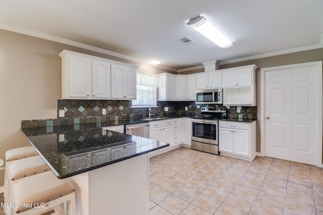 28121 Dusty Ln, Picayune, MS 39466 - kitchen with stainless steel appliances, a peninsula, a sink, a breakfast bar area, and ornamental molding