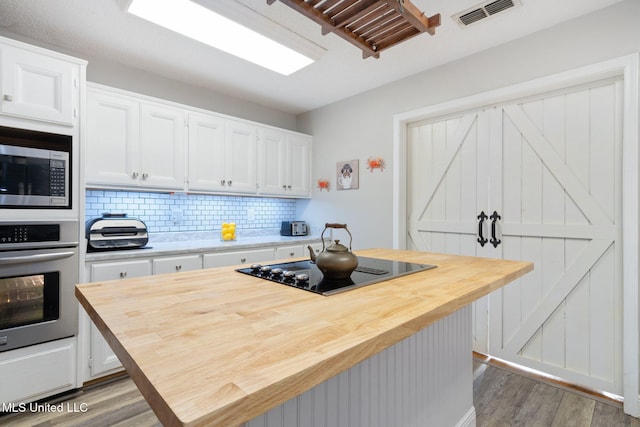 kitchen with dark wood-type flooring, stainless steel appliances, tasteful backsplash, butcher block countertops, and white cabinetry