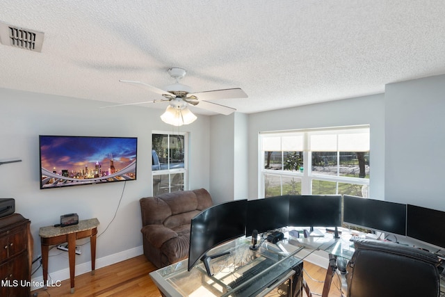 living room with a textured ceiling, ceiling fan, and hardwood / wood-style flooring