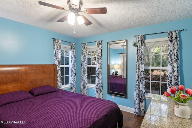 bedroom featuring multiple windows, a textured ceiling, ceiling fan, and dark hardwood / wood-style floors