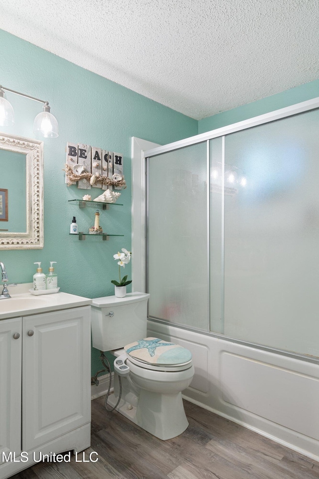 full bathroom featuring a textured ceiling, enclosed tub / shower combo, hardwood / wood-style floors, and vanity