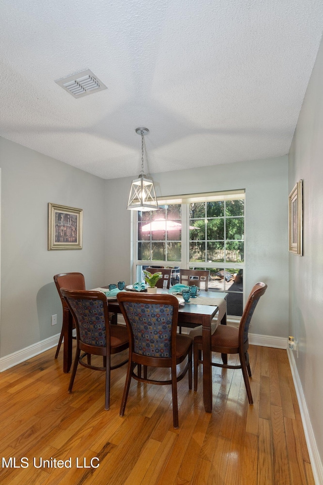 dining space featuring a textured ceiling and wood-type flooring