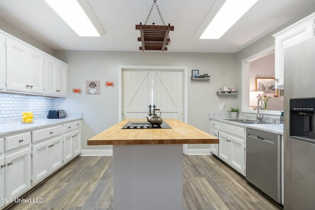 kitchen featuring dishwasher, a center island, white cabinetry, tasteful backsplash, and butcher block counters