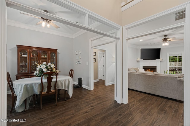 32 Cambrooke, Hattiesburg, MS 39402 - dining area featuring ceiling fan, ornamental molding, dark wood-style flooring, baseboards, and a lit fireplace