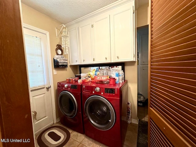 clothes washing area with independent washer and dryer, light tile patterned flooring, a textured ceiling, and cabinets