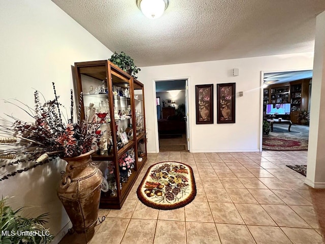 hallway with a textured ceiling and light tile patterned floors