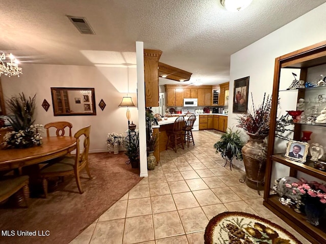 dining area with a chandelier, a textured ceiling, and light tile patterned floors