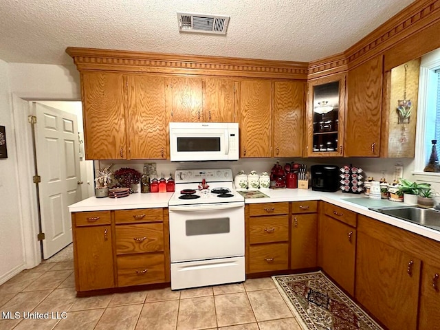 kitchen featuring a textured ceiling, light tile patterned floors, and white appliances