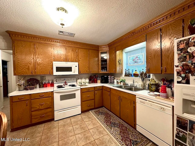 kitchen featuring white appliances, light tile patterned flooring, a textured ceiling, and sink