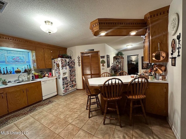 kitchen featuring a kitchen breakfast bar, a textured ceiling, sink, and white appliances