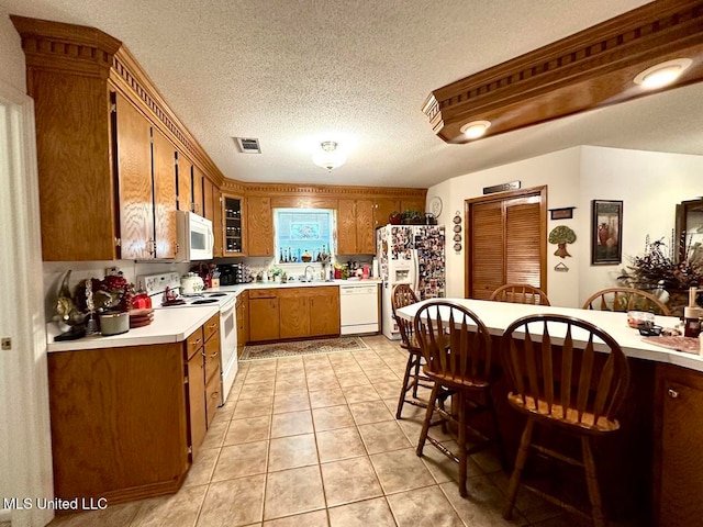 kitchen with sink, a textured ceiling, white appliances, and light tile patterned floors