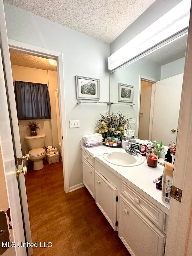 bathroom with vanity, a textured ceiling, wood-type flooring, and toilet