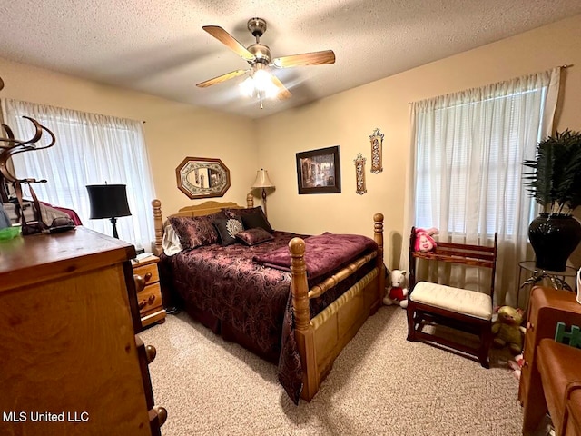 bedroom featuring a textured ceiling, light colored carpet, and ceiling fan