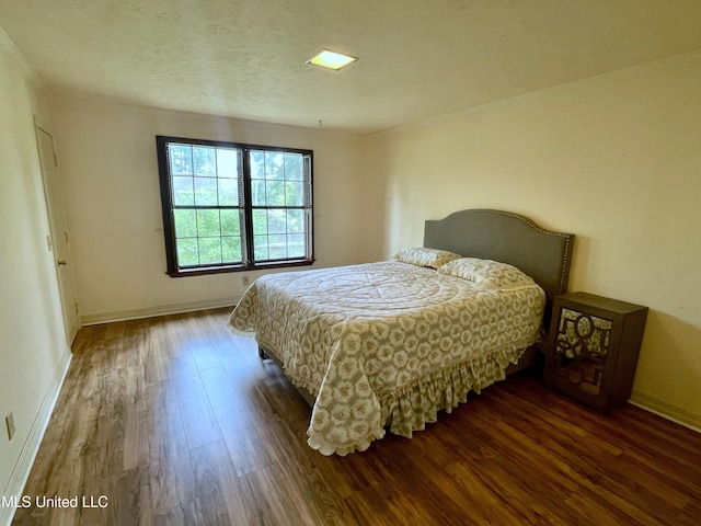 bedroom with a textured ceiling and dark hardwood / wood-style flooring