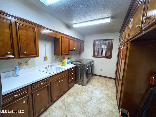 laundry area with washer and dryer, sink, light tile patterned flooring, a textured ceiling, and cabinets