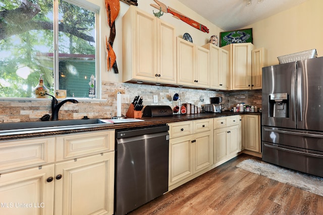 kitchen with cream cabinetry, light hardwood / wood-style flooring, stainless steel appliances, a textured ceiling, and tasteful backsplash