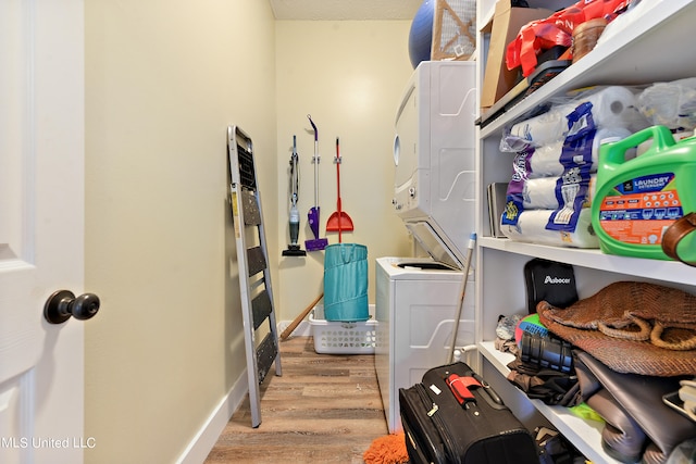 washroom with light hardwood / wood-style flooring and stacked washer and clothes dryer