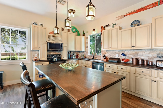 kitchen with tasteful backsplash, hanging light fixtures, dark hardwood / wood-style flooring, a kitchen island, and black appliances