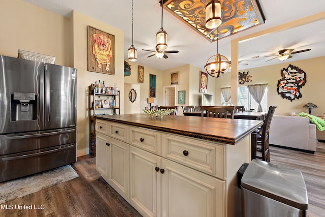 kitchen with cream cabinetry, a kitchen island, wooden counters, dark hardwood / wood-style floors, and stainless steel refrigerator with ice dispenser