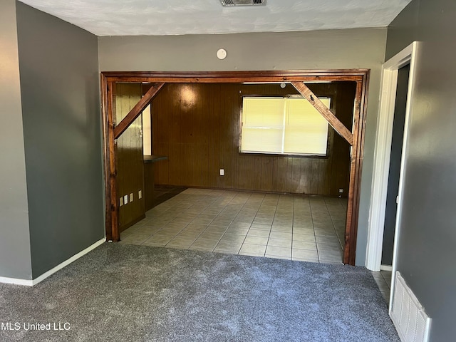 carpeted empty room featuring wood walls