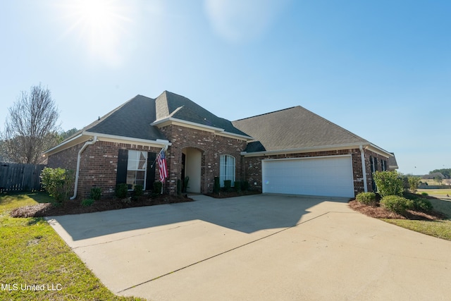 traditional-style home with brick siding, fence, concrete driveway, roof with shingles, and a garage