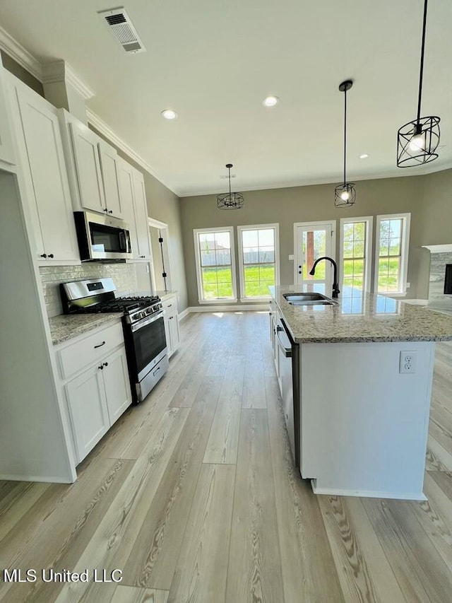 113 River Bend Ave, Vidalia, LA 71373 - kitchen with a kitchen island with sink, a sink, white cabinets, appliances with stainless steel finishes, and pendant lighting