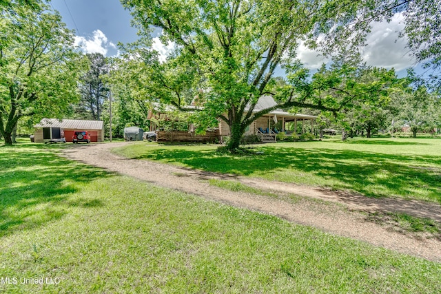 106 Mcwilliams Dr, Terry, MS 39170 - view of grassy yard with driveway, an outdoor structure, view of scattered trees, and a porch