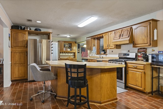 5539 Gates Ave, Long Beach, MS 39560 - kitchen featuring stainless steel appliances, light countertops, open shelves, wood finish floors, and a textured ceiling