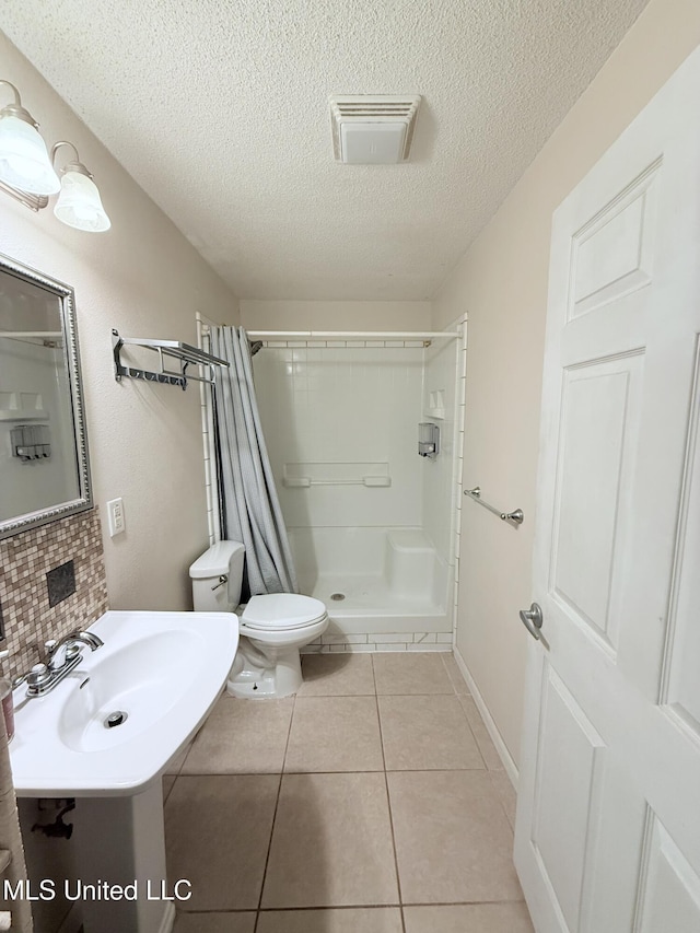 3908 Wildwood Rd, Moss Point, MS 39562 - bathroom featuring a stall shower, a textured ceiling, tile patterned floors, and tasteful backsplash