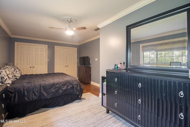 bedroom with ceiling fan, crown molding, multiple closets, and hardwood / wood-style flooring