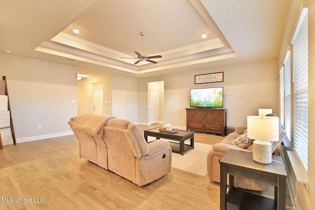 living room featuring a tray ceiling, light hardwood / wood-style flooring, and ornamental molding