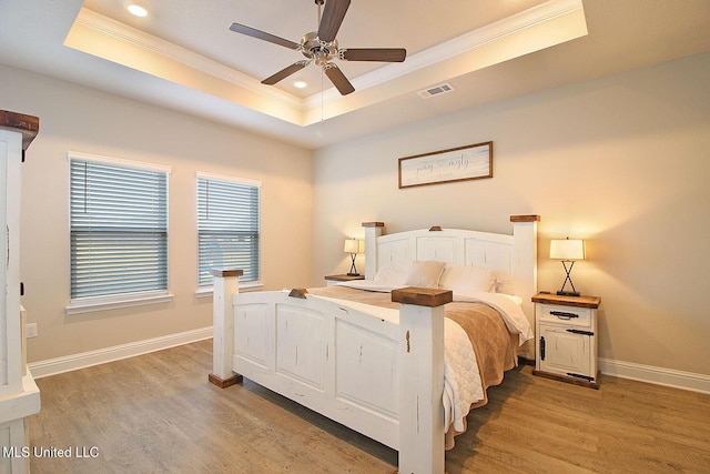 bedroom featuring crown molding, wood-type flooring, a raised ceiling, and ceiling fan