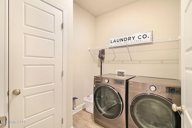 clothes washing area with separate washer and dryer and light hardwood / wood-style floors